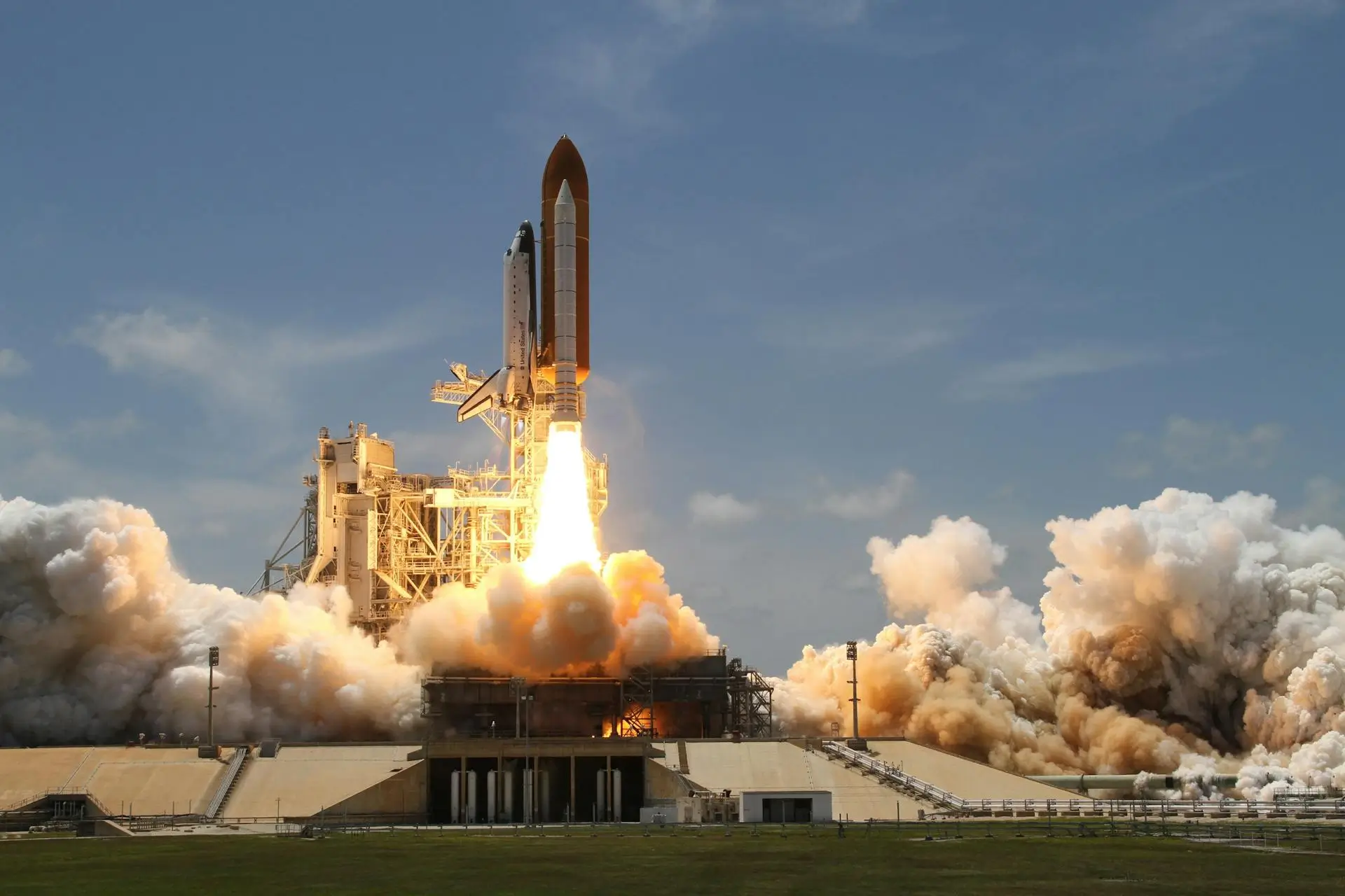 Kaviapps-wordpress-speed-optimize-banner-image A space shuttle is launching from a pad, with bright flames and smoke billowing out from its engines. The sky is clear and blue, and the launch pad structure is visible, surrounded by a grassy field.