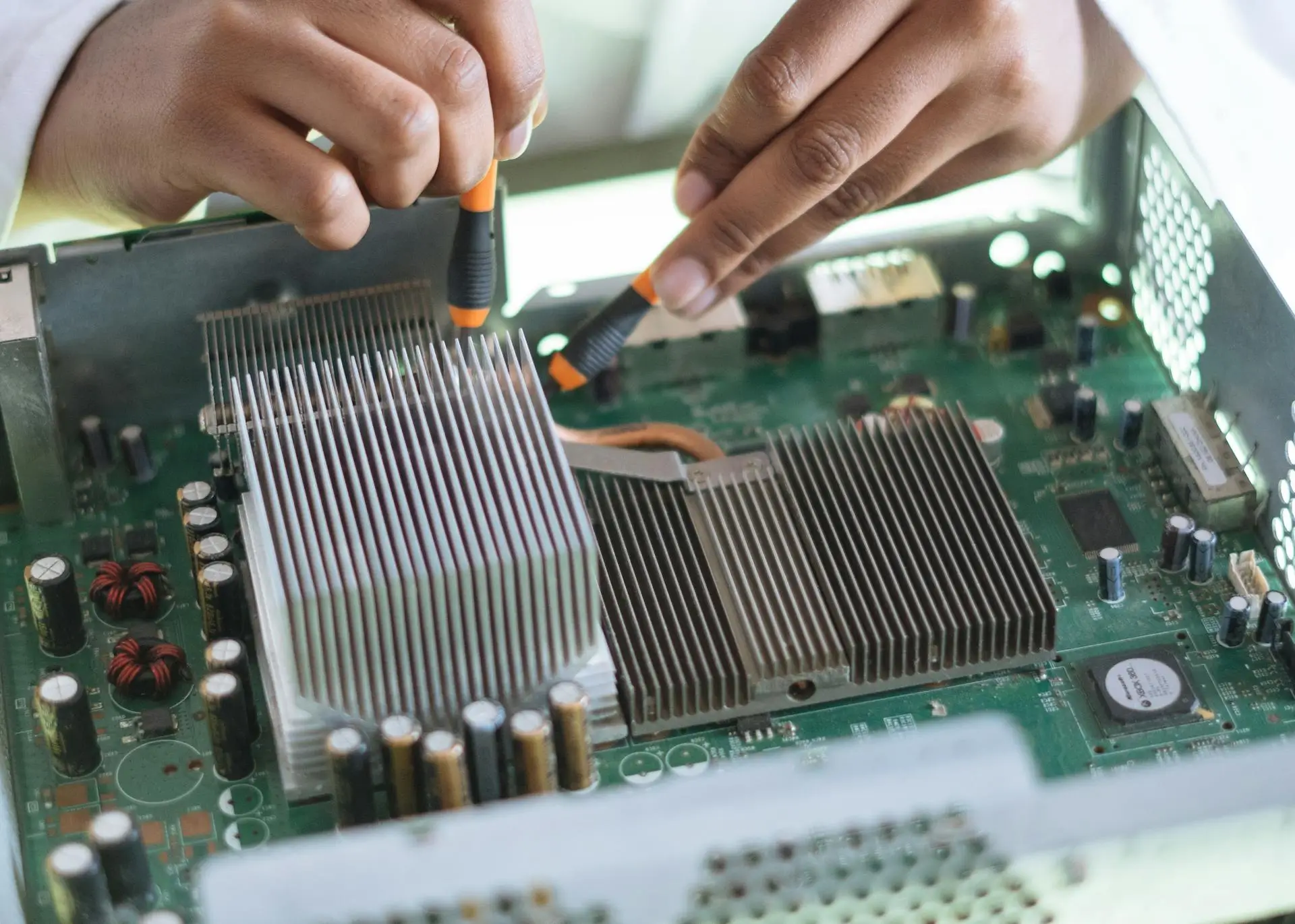 Kaviapps-wordpress-theme-Customization-main-banner A person uses tools to work on a computer motherboard, adjusting the heatsink inside a metal casing. The image shows a close-up of their hands focusing on electronic components and connections.